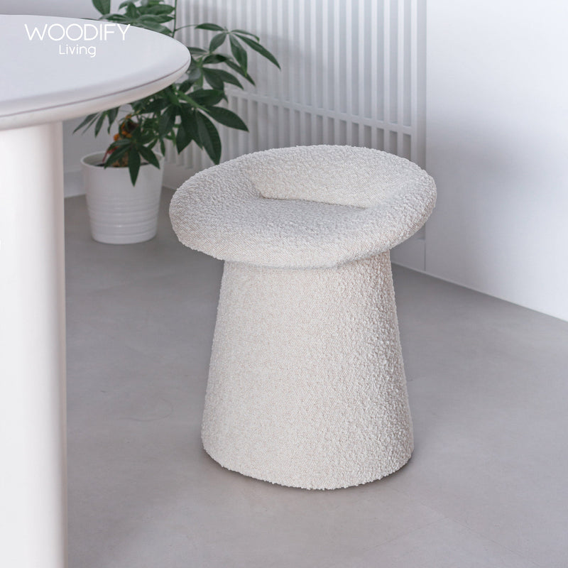 White textured stool in a minimalistic room with a plant and table.