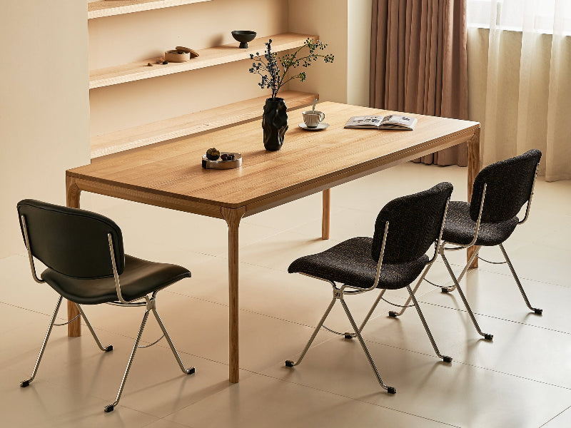Modern dining area with wooden table and black chairs against a neutral wall.