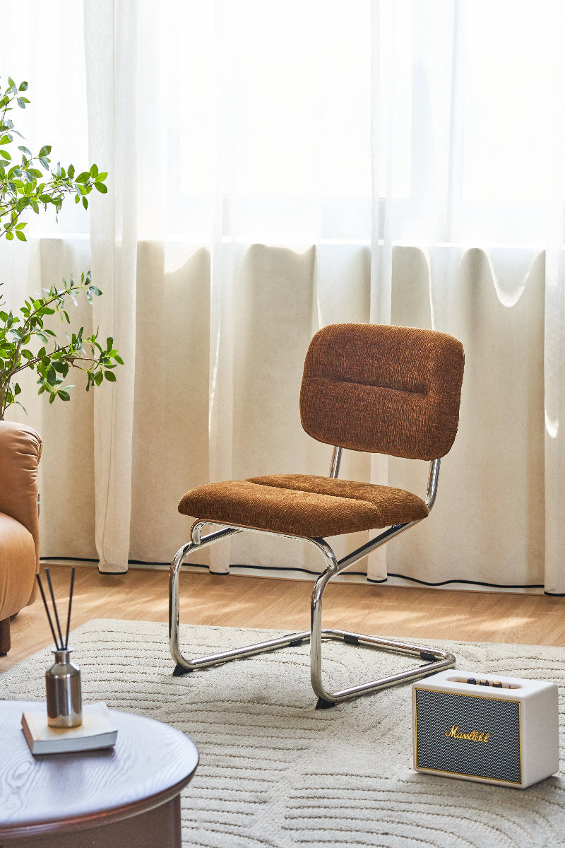 Brown chair in a living room with a plant, coffee table, and white curtains.