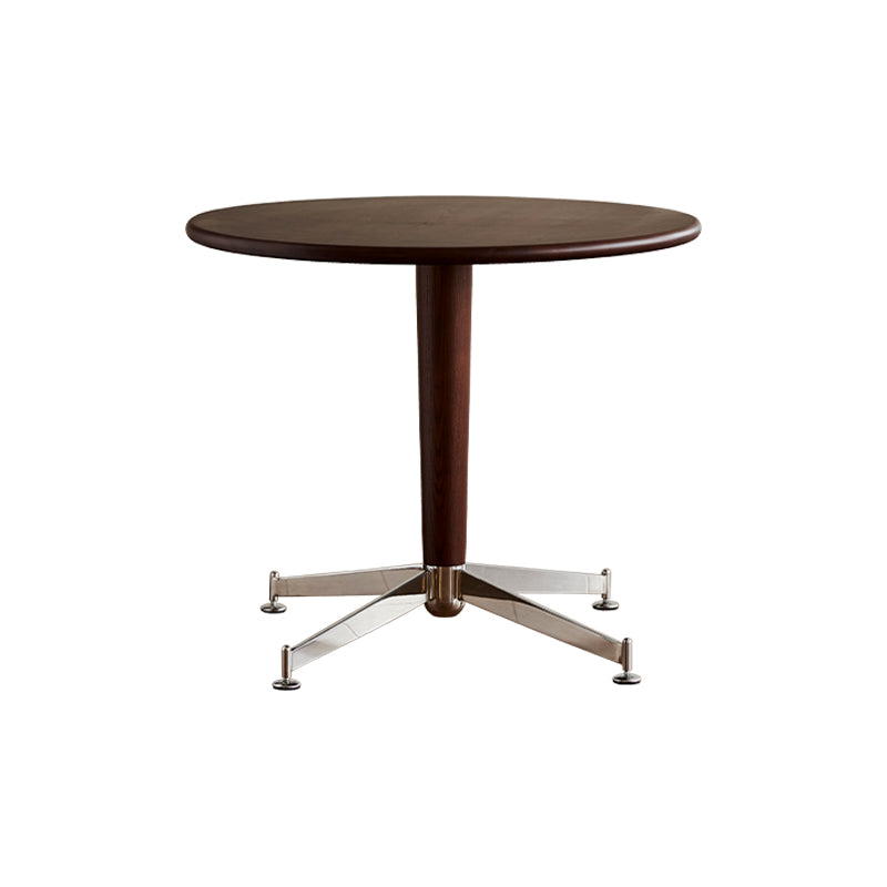 A round dining table with a dark wood tabletop and a metallic silver leg base.