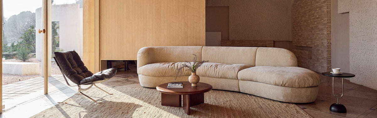 Modern living room with a beige sectional sofa, wooden coffee table, and a chair.
