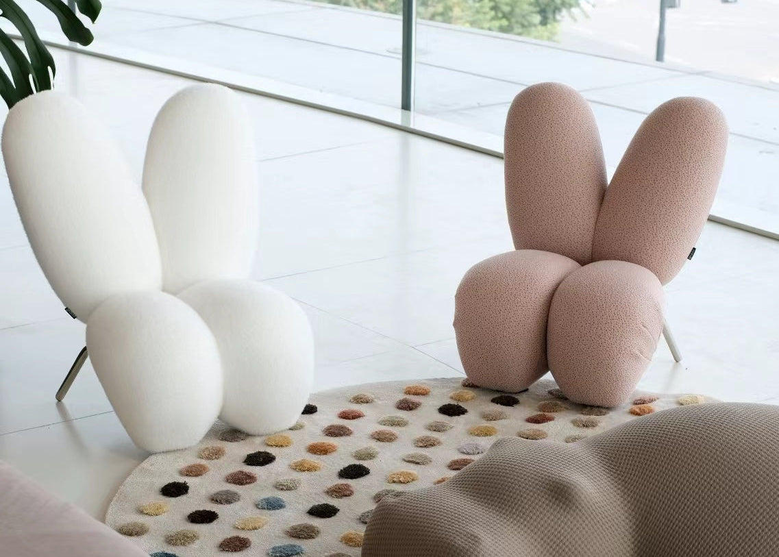 Modern interior with a unique pink bunny-shaped chair on a colorful rug.