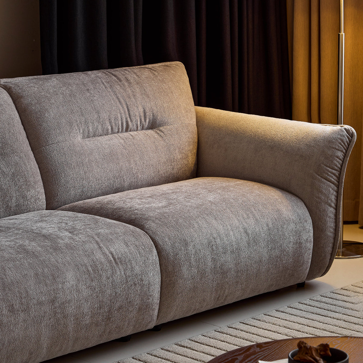 Gray sofa in a room with dark curtains and a lamp.