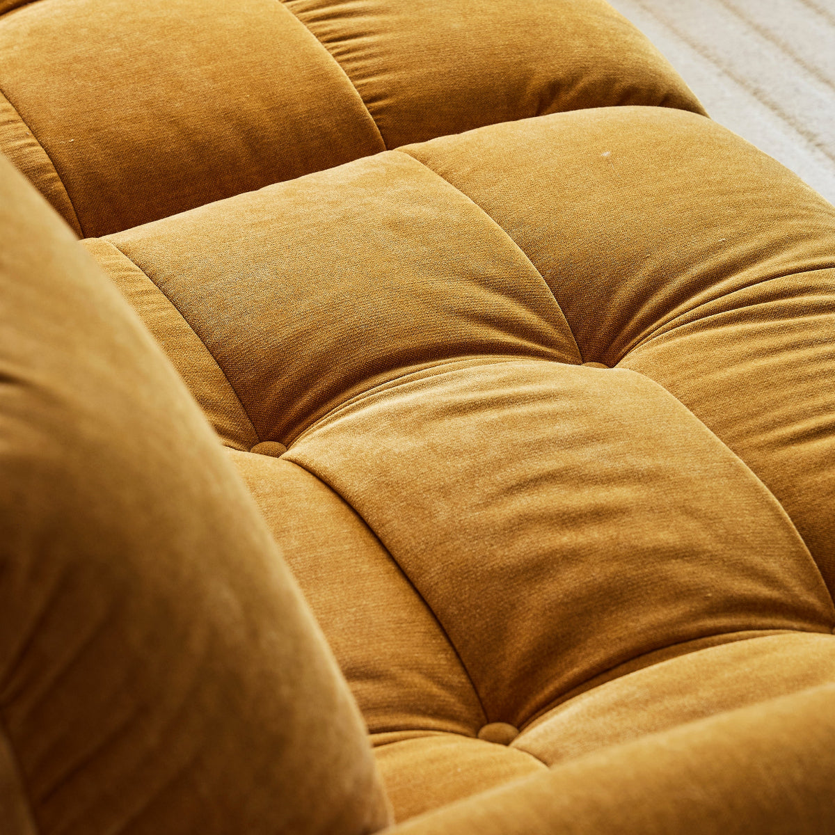 Close-up of a mustard yellow sofa with tufted cushions.