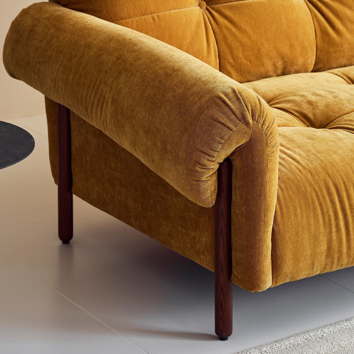 Mustard yellow sofa with wooden armrests on a light gray floor.