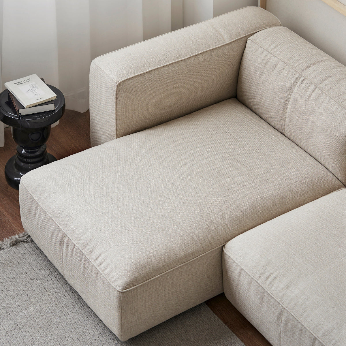 Beige sectional sofa in a room with a striped wall and small table.