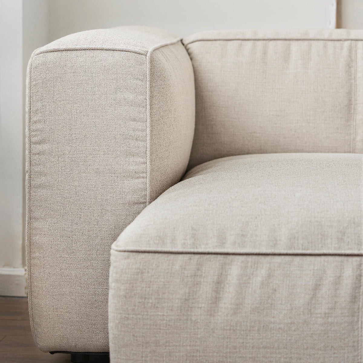 Beige sofa corner in a minimalistic room with white walls.