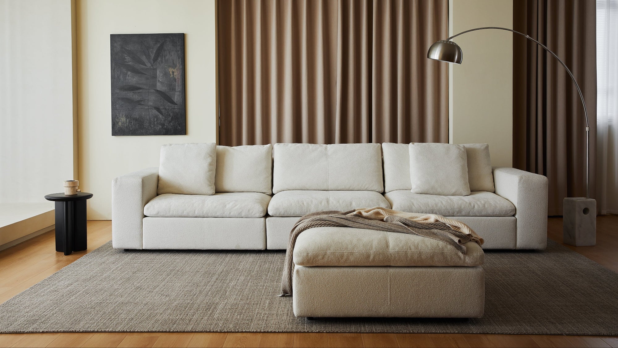 Modern living room with a white sectional sofa, ottoman, and decorative elements.