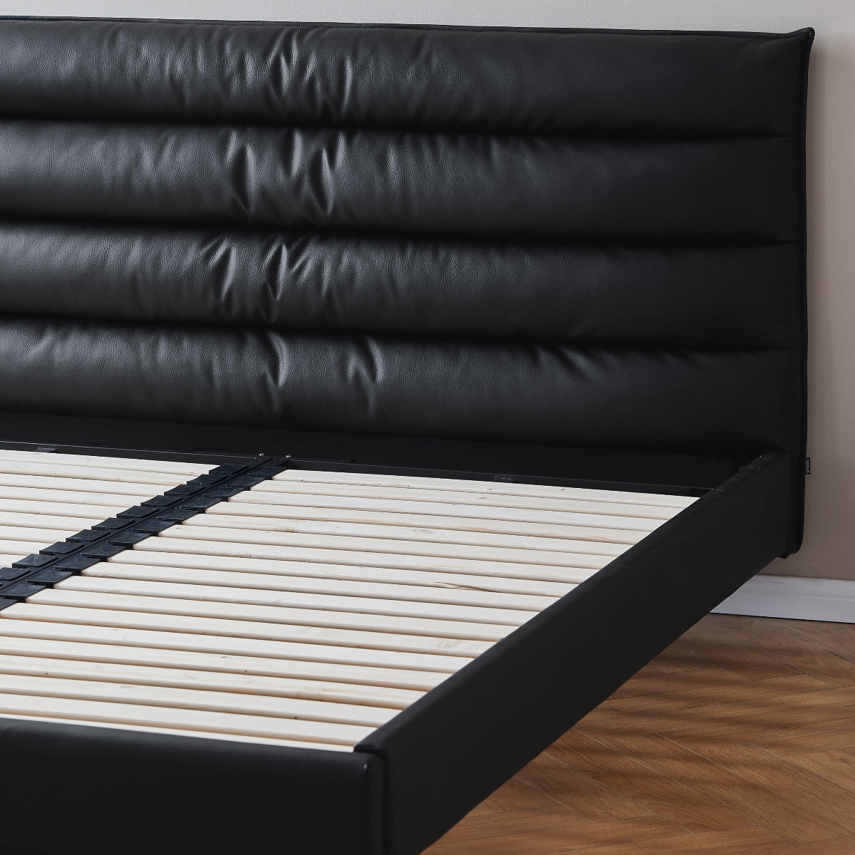 Black leather bed frame against a white wall