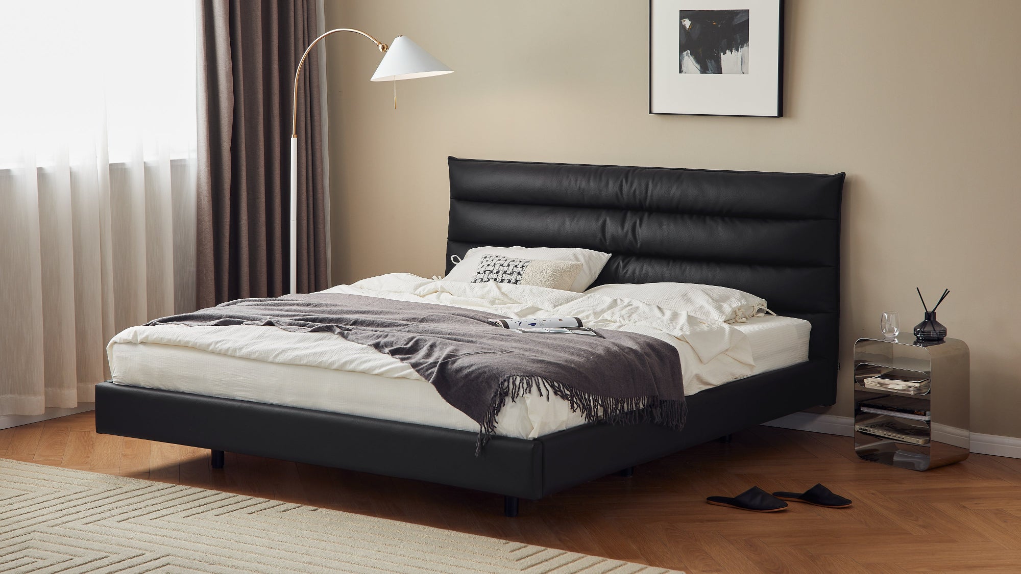 Modern bedroom with a black leather bed, nightstand, and lamp.