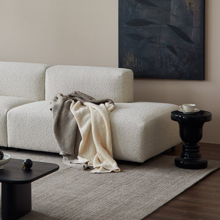 Modern living room with a white sofa, black coffee table, and abstract art on the wall.