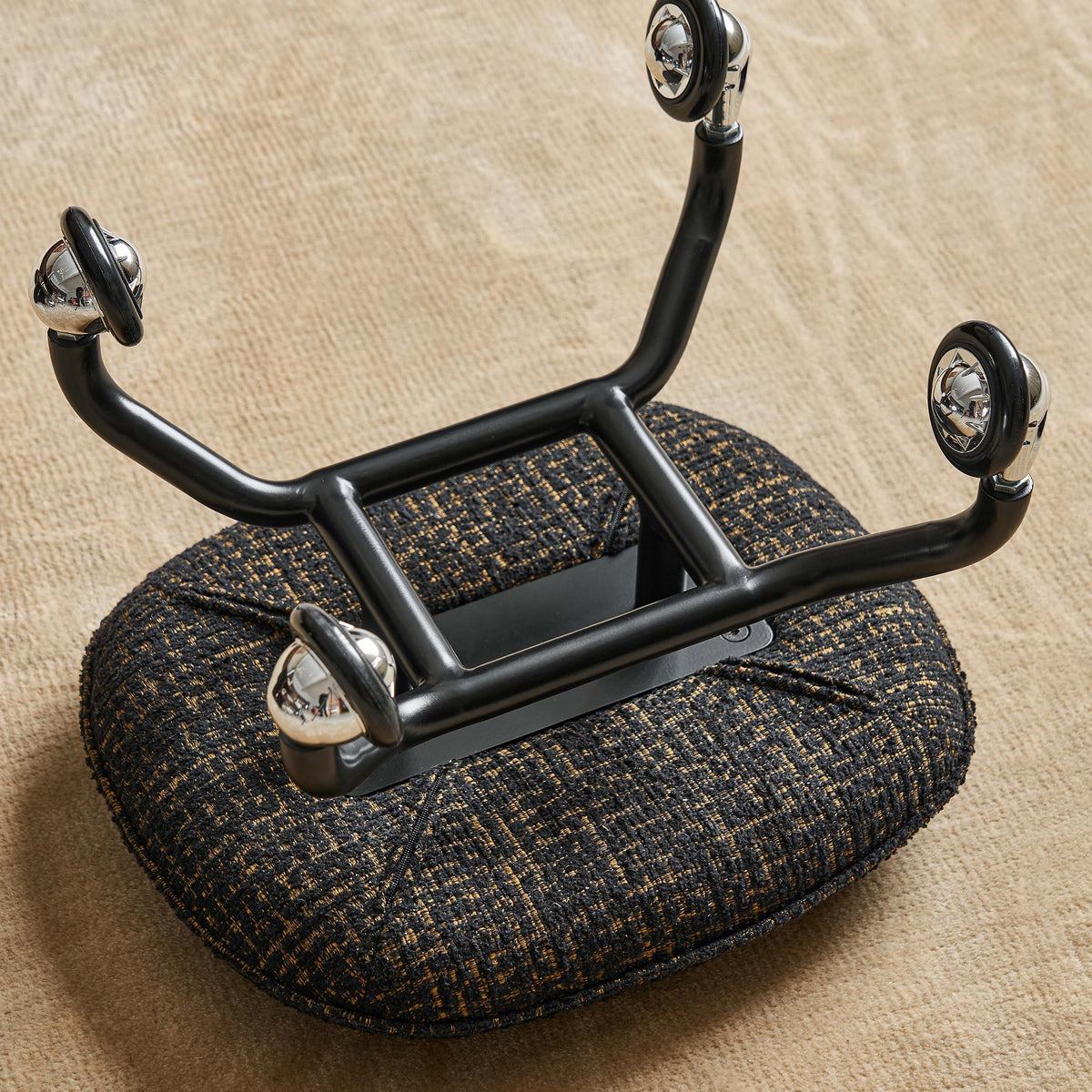 Black metal frame with textured brown cushion on a beige surface