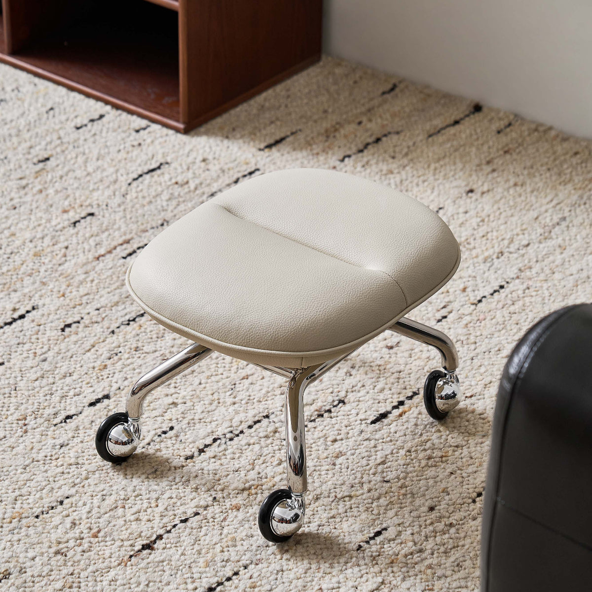 White office ottoman on wheels in a room with a bookshelf and carpet.