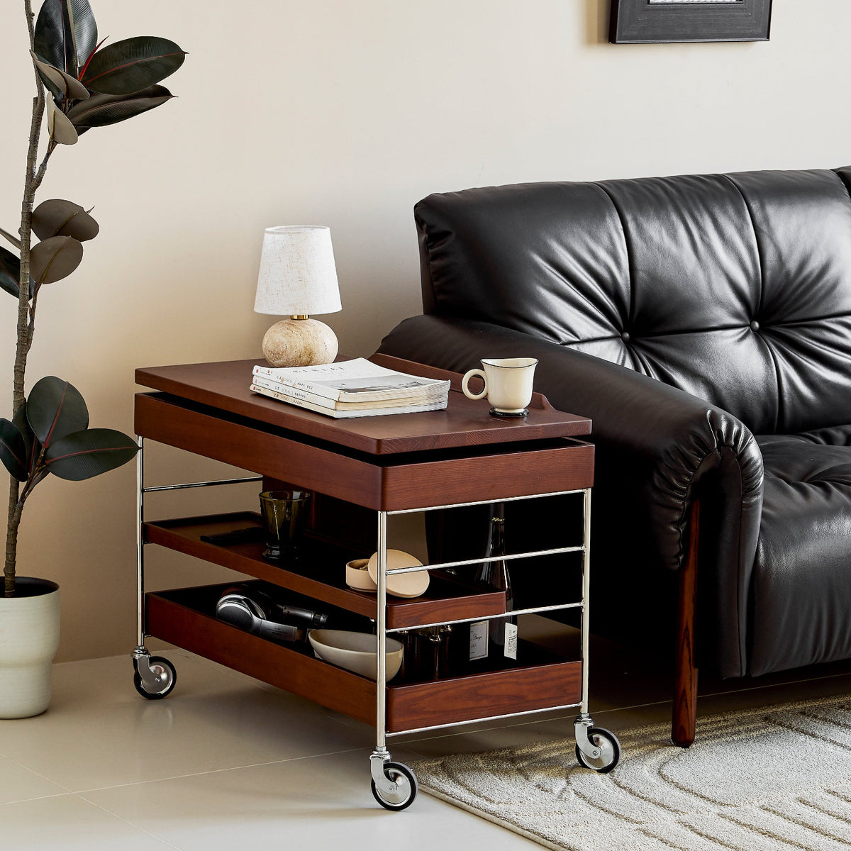 Living room with a black leather sofa, wooden side table, and decorative items.