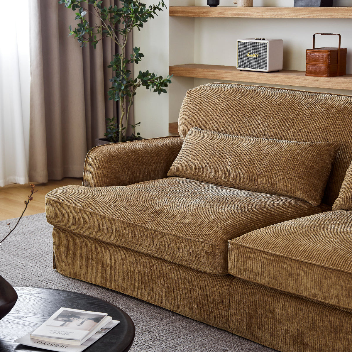 Brown sofa in a living room with a coffee table and shelves in the background.