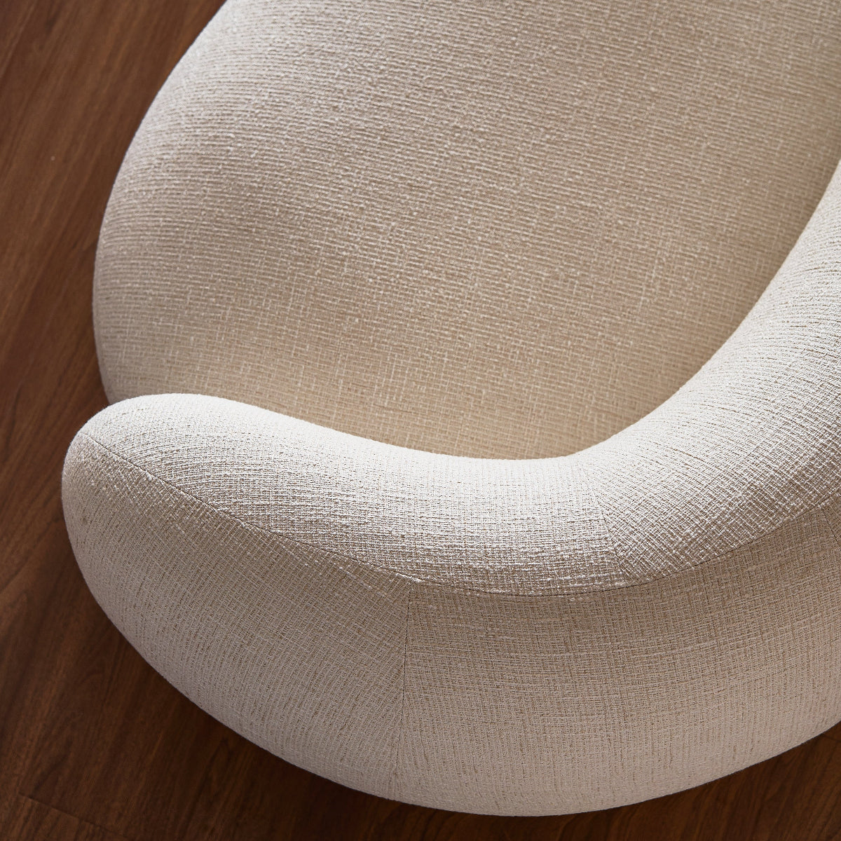 Close-up of a beige upholstered chair on a wooden floor