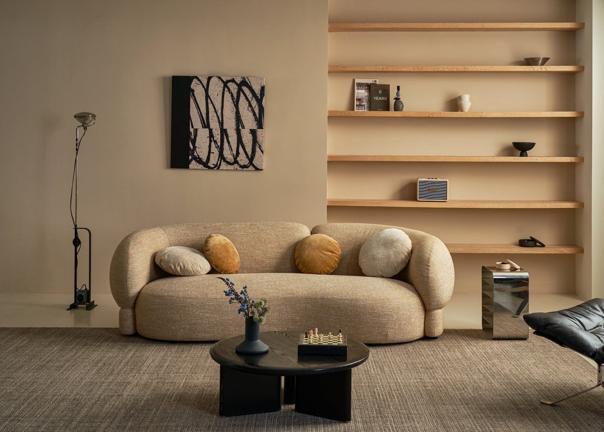 Modern living room with a beige sofa, coffee table, and shelves.