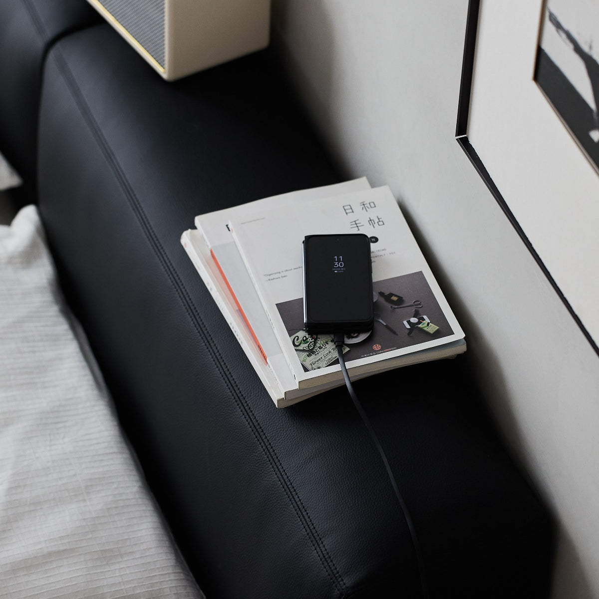 Small speaker on a black leather chair next to a stack of books