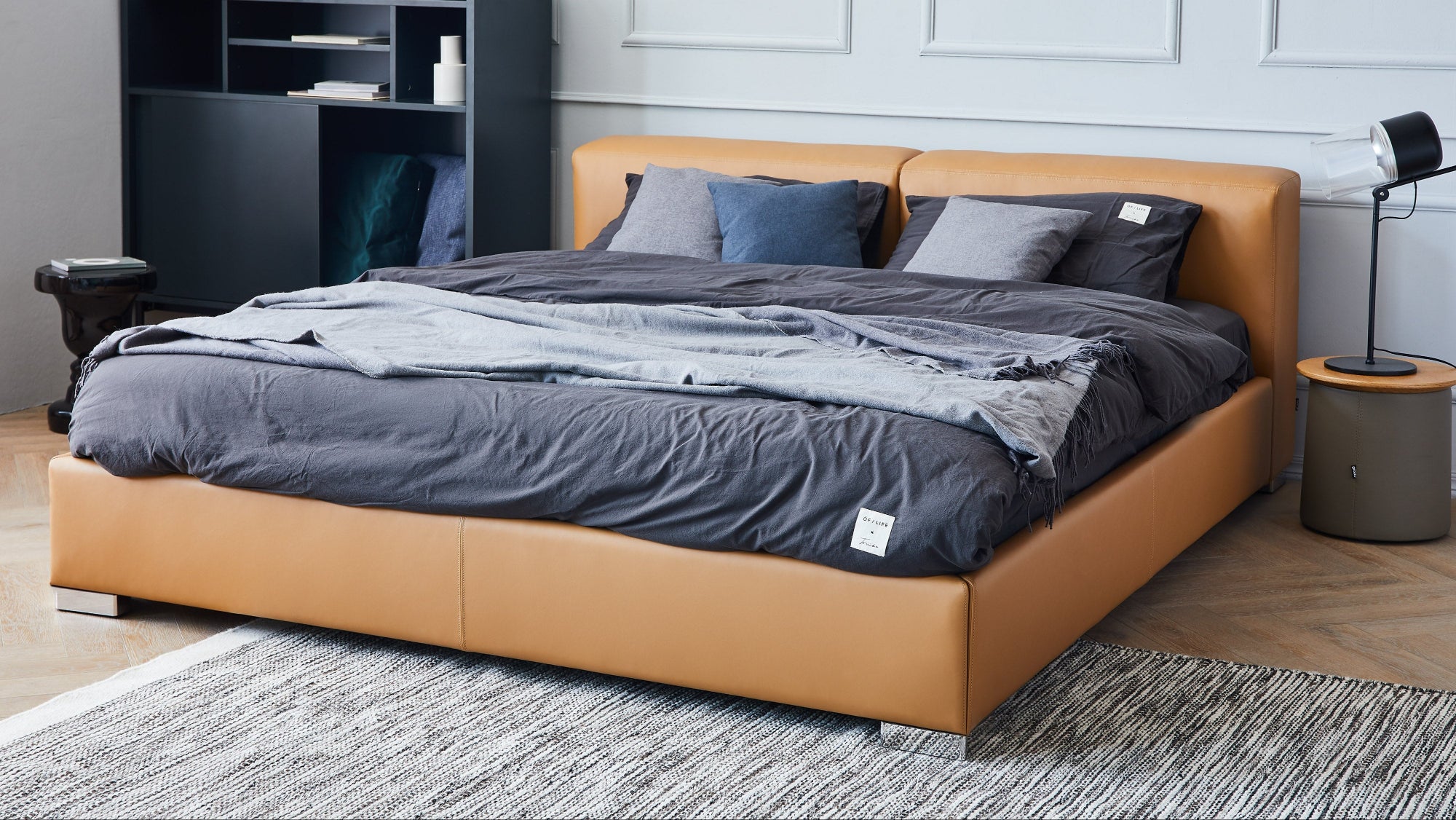 Brown leather bed with gray bedding in a room setting