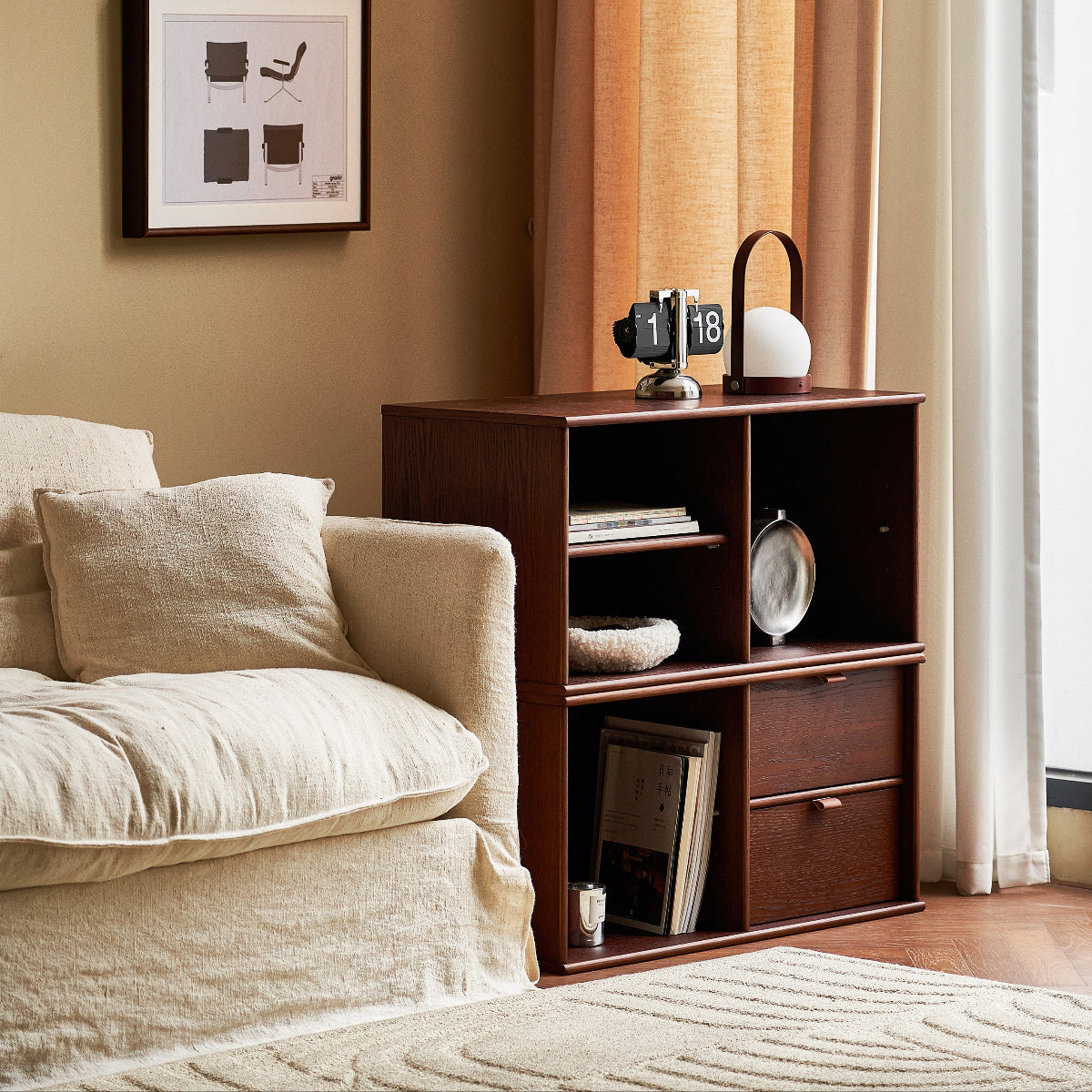 Living room with a brown bookshelf, beige sofa, and framed pictures on the wall.