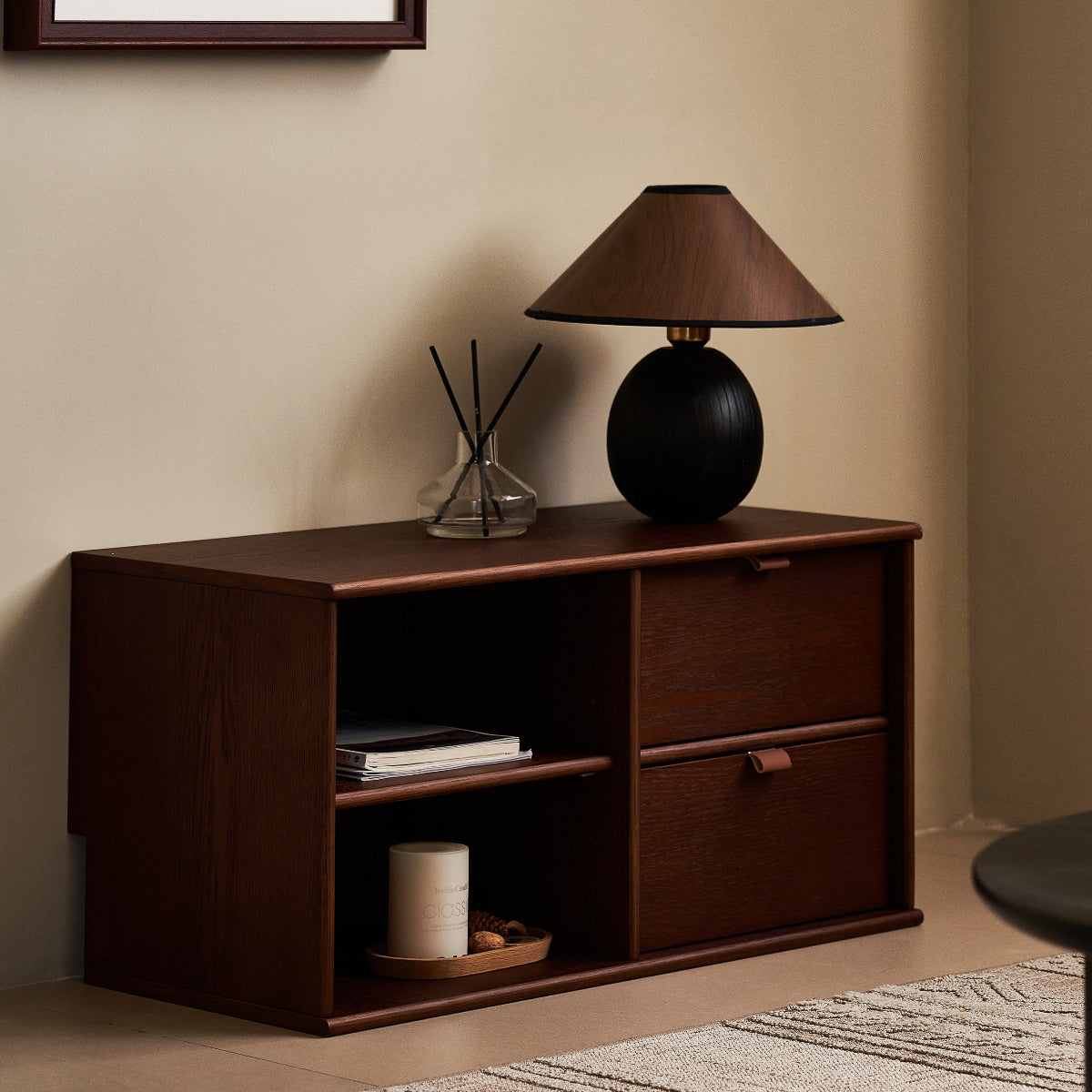 Wooden sideboard with a lamp and decorative items in a room setting.