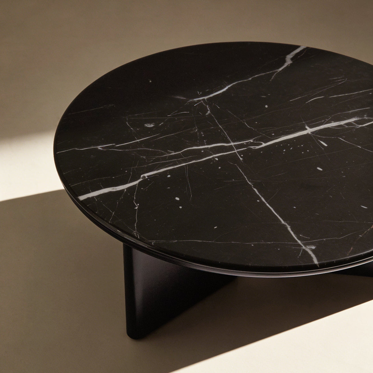 Round black marble coffee table on a beige background