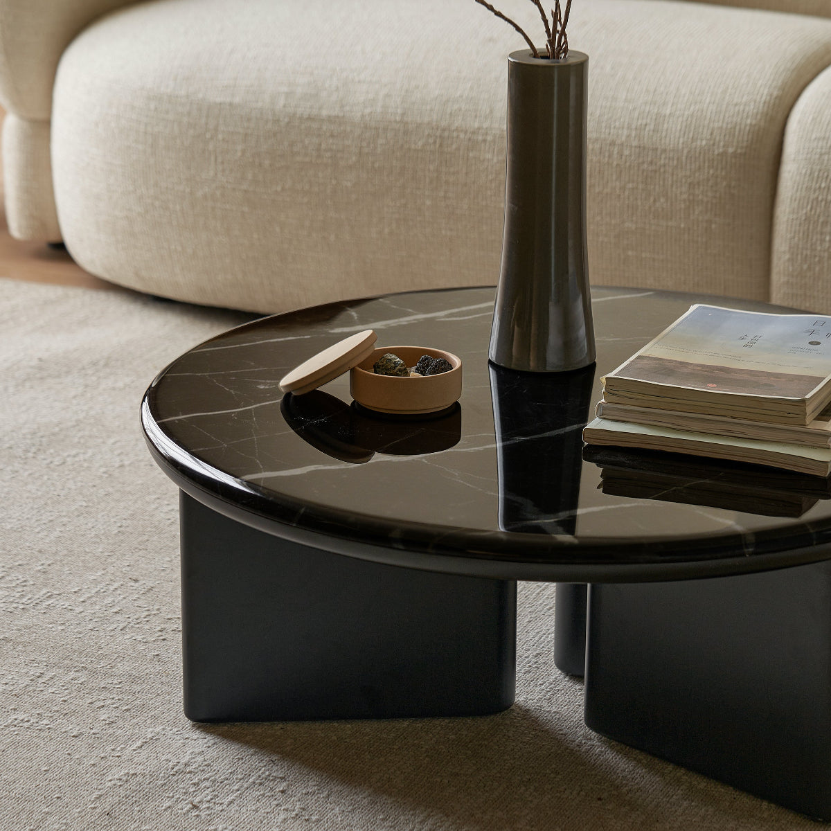 Modern living room with a black coffee table, vase with flowers, and books.