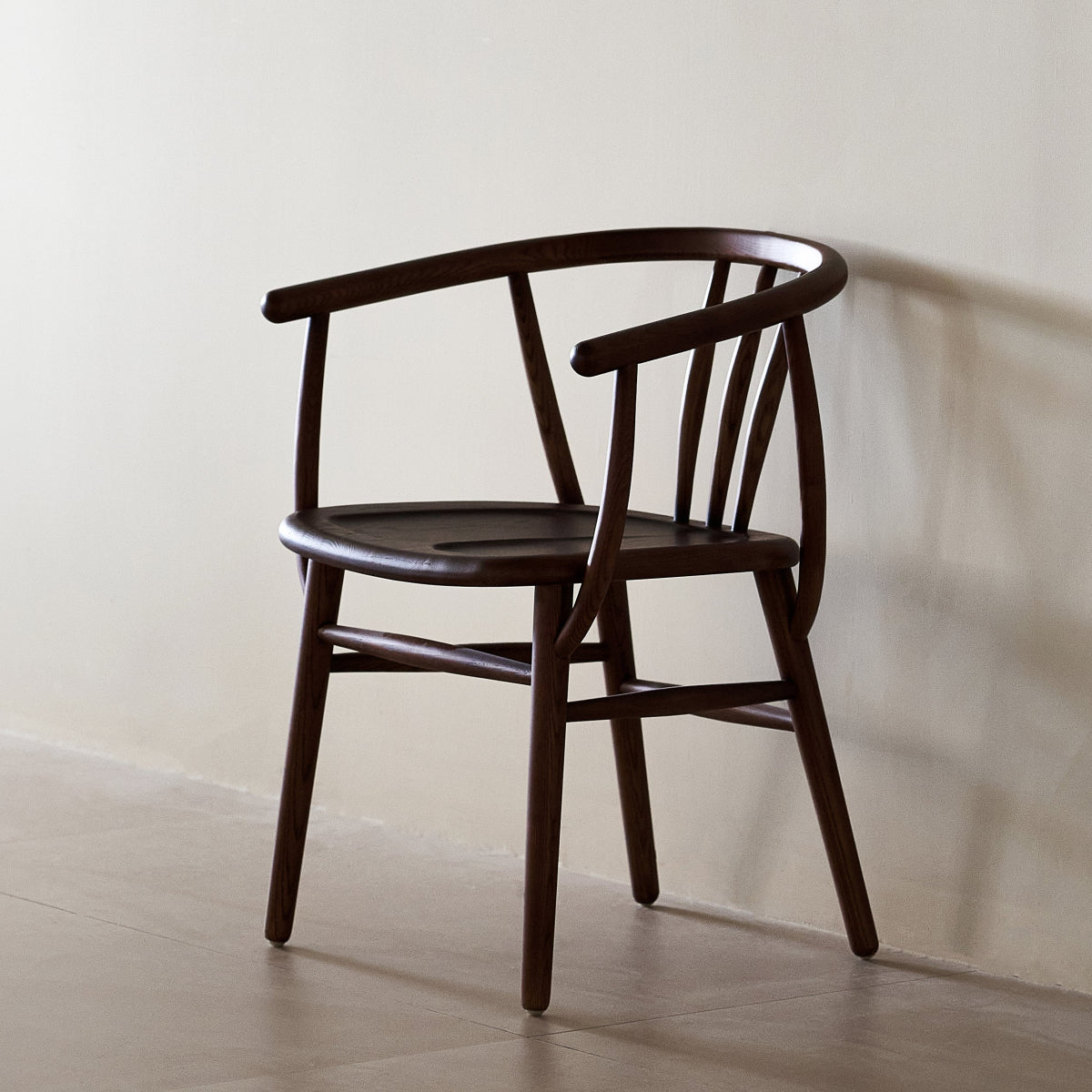 Wooden chair against a plain wall with a soft shadow on the floor.