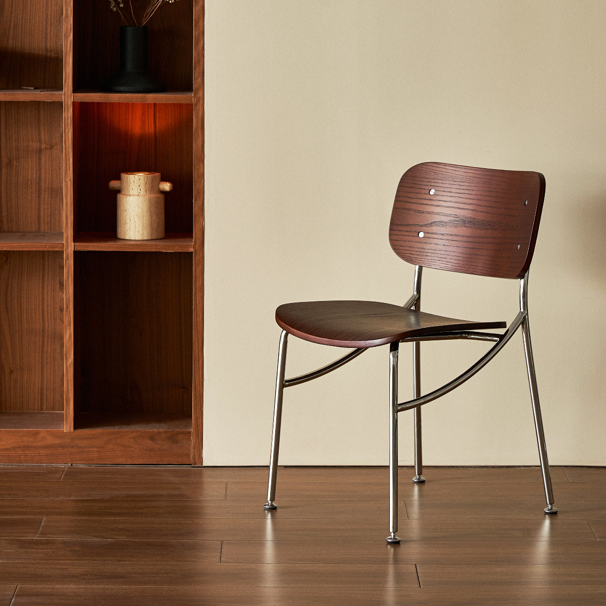Wooden chair with metal legs in a room with wooden bookshelf and beige wall.