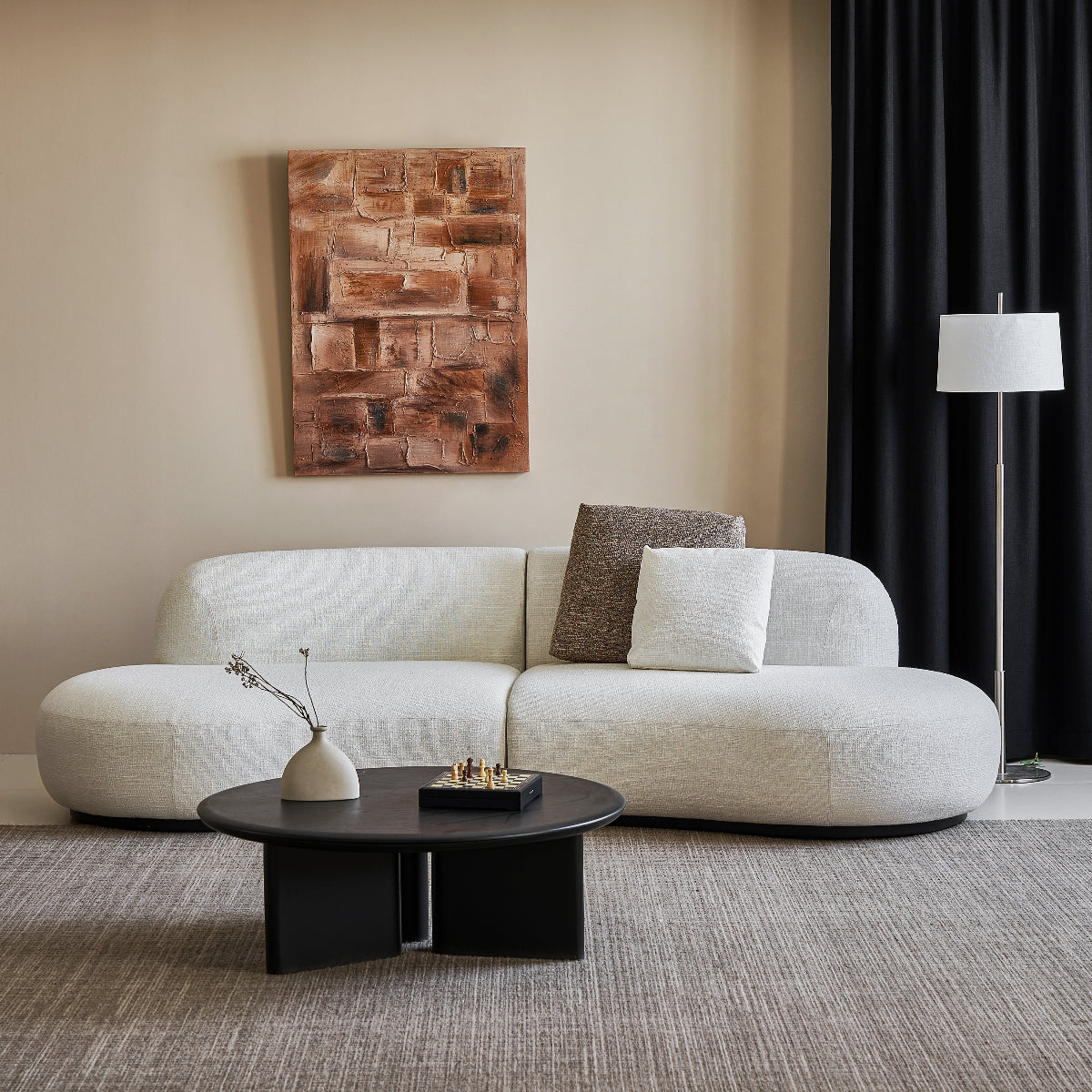 Modern living room with a white sofa, round coffee table, and abstract wall art.