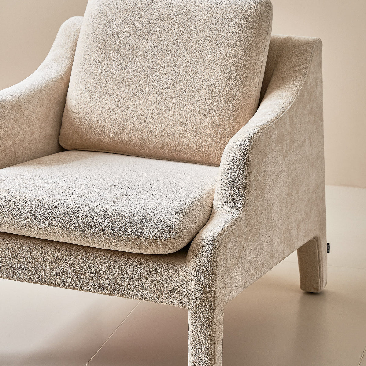 Beige armchair on a light beige floor with a neutral background