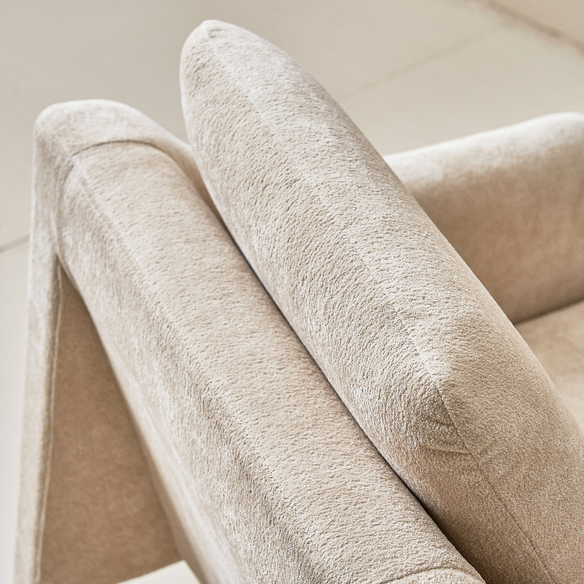 Close-up of a beige upholstered chair with a soft texture.