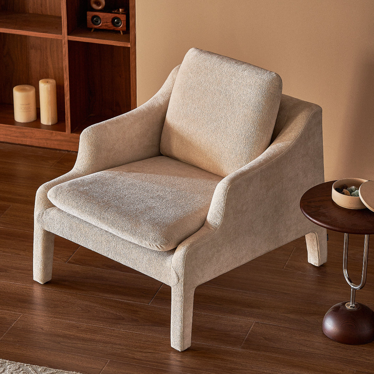 Beige armchair in a room with wooden floor and bookshelf.