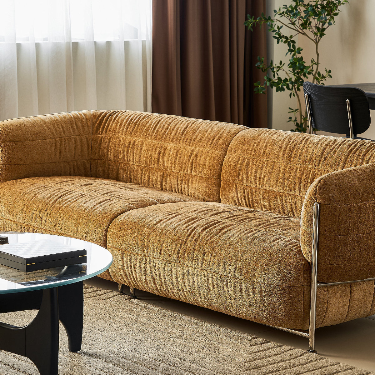 Brown velvet sofa in a living room setting with a coffee table and plant.