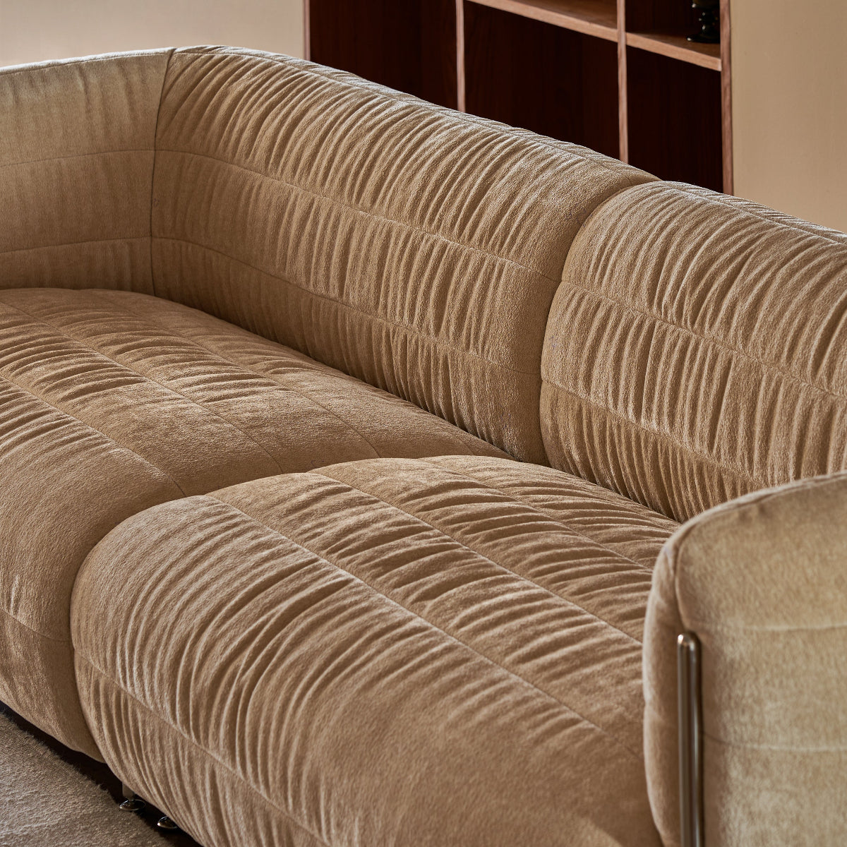 Beige textured sofa in a room with a bookshelf in the background.