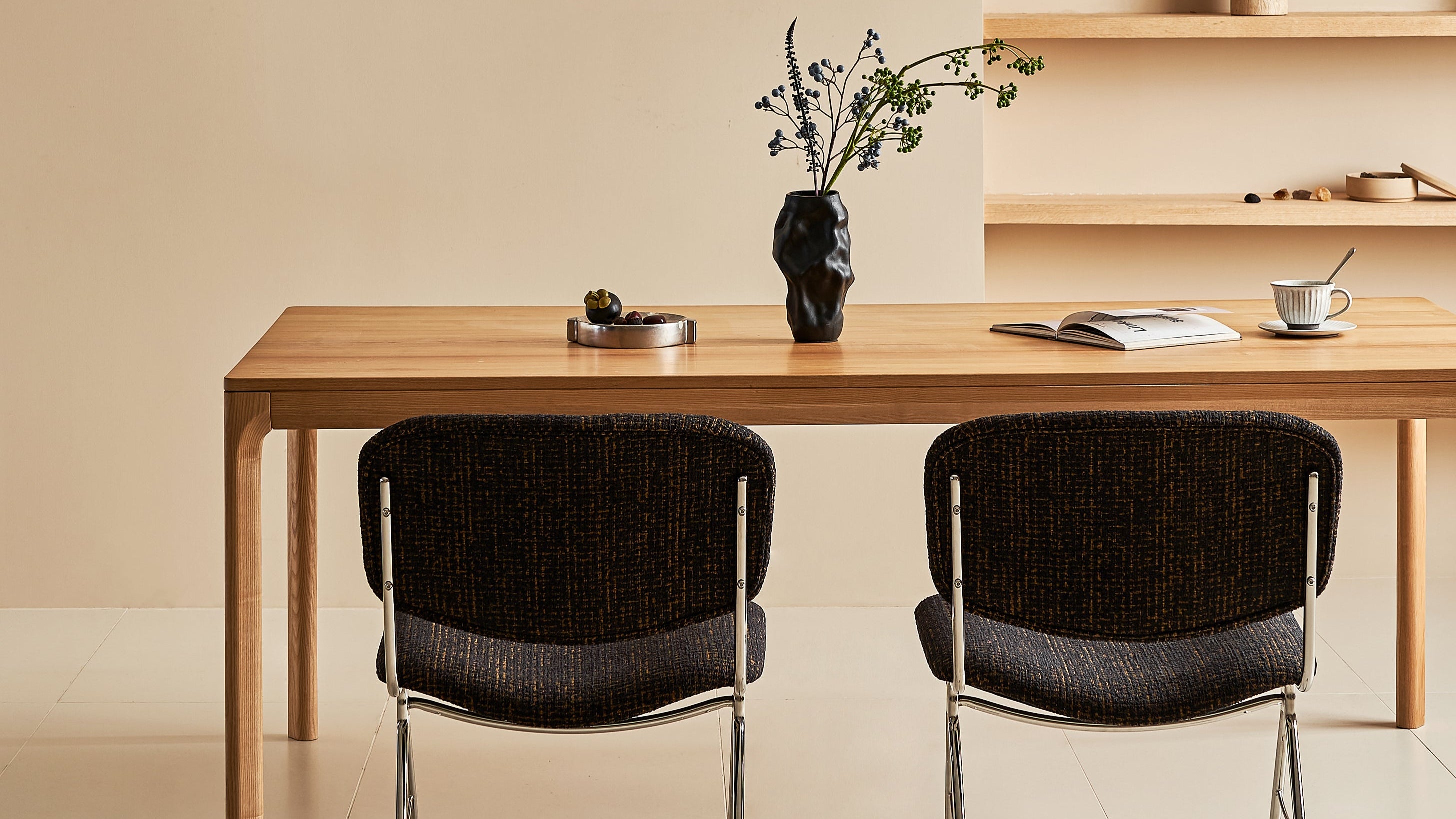 Modern dining area with wooden table and black chairs against a beige wall.