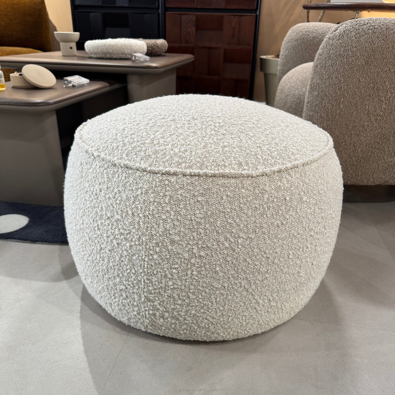 Close-up of a textured gray ottoman in a room with furniture and decor.