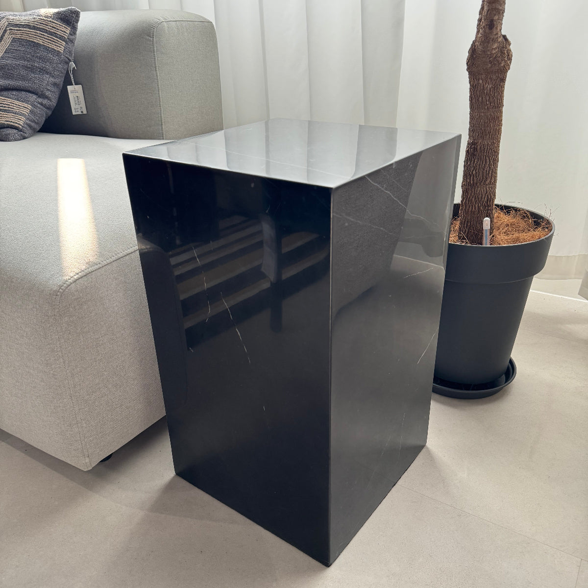 Modern black wall-mounted shelf against a white wall with a decorative branch on top.