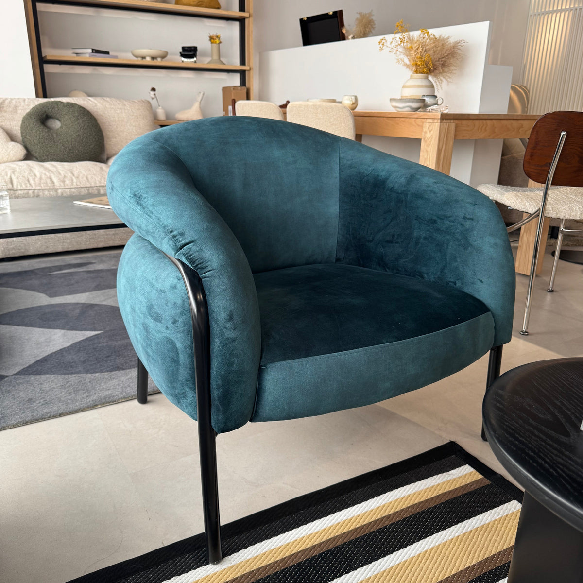 Blue armchair in a modern living room setting with a striped rug.