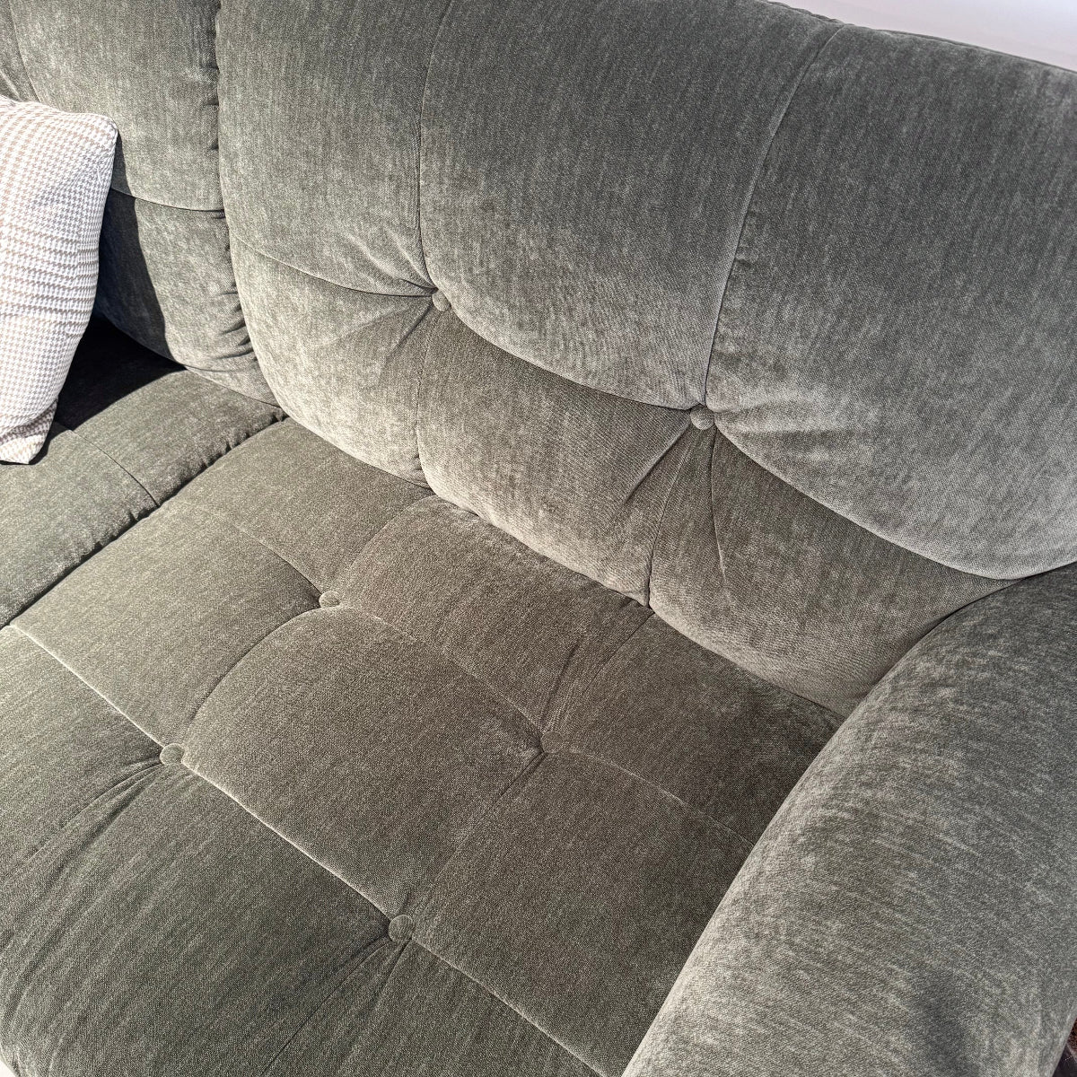 Gray tufted sofa with a cushioned backrest