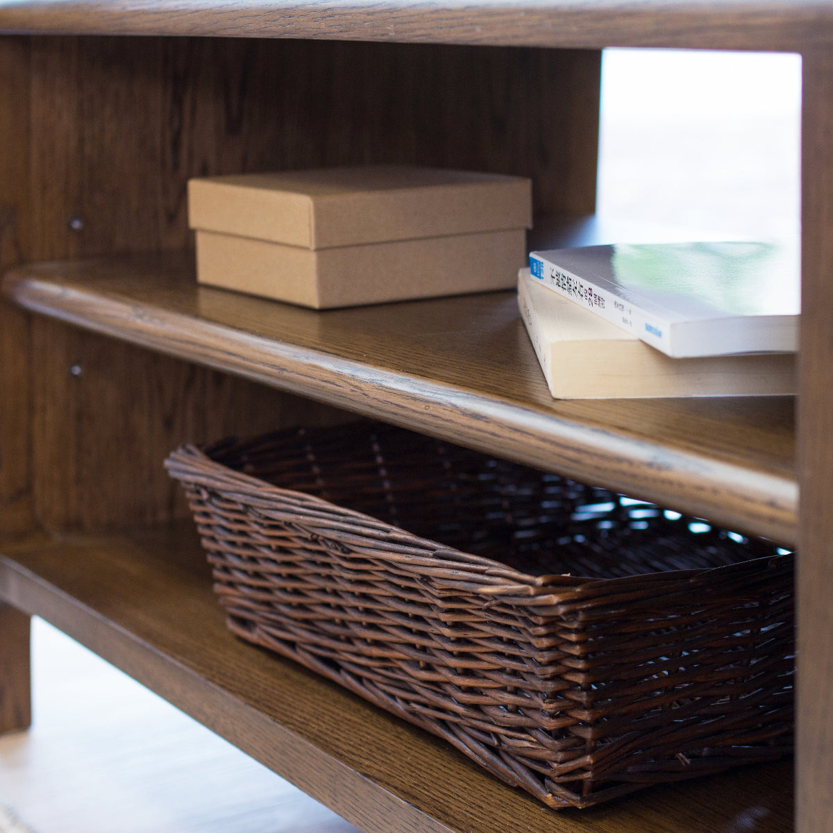 Wooden shelf with a basket and books on a light-colored floor