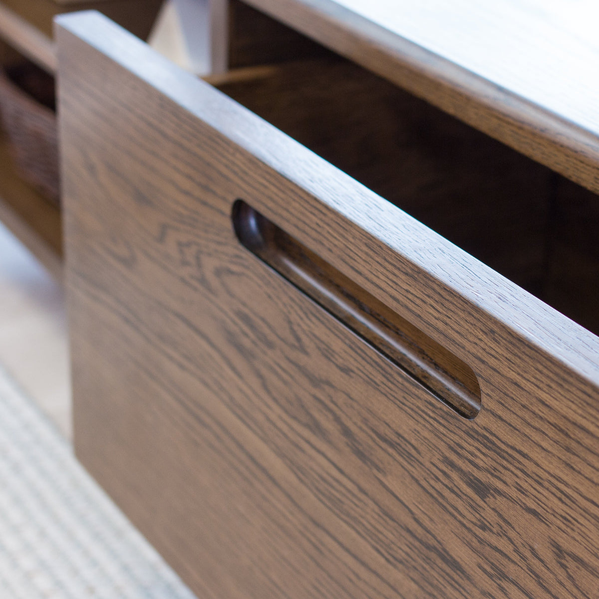 Close-up of a wooden drawer with a handle on a light-colored surface.