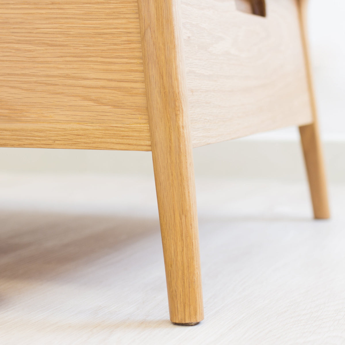Wooden chair leg on a white floor with a brown cushion.