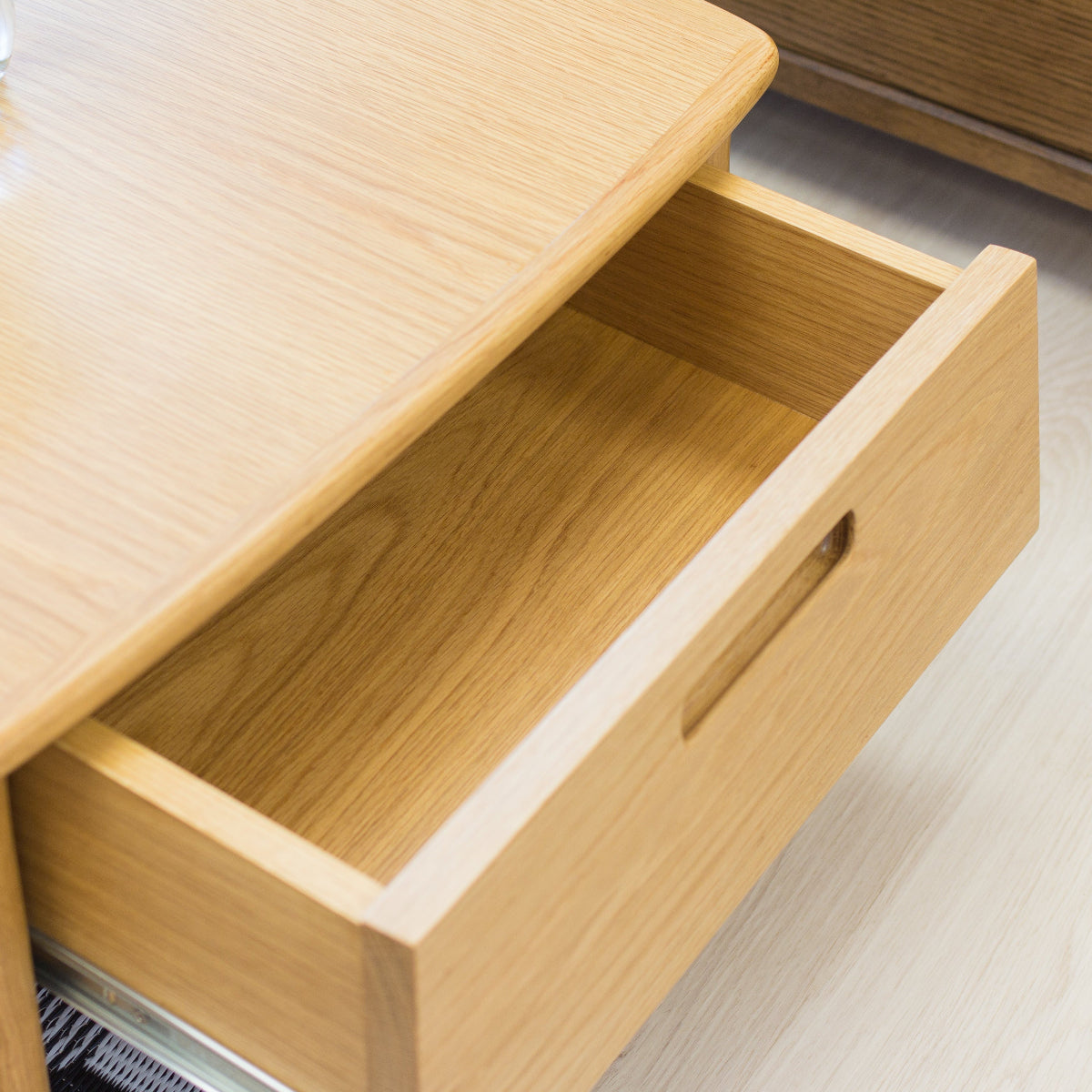 Wooden drawer unit with an open drawer on a light-colored floor.