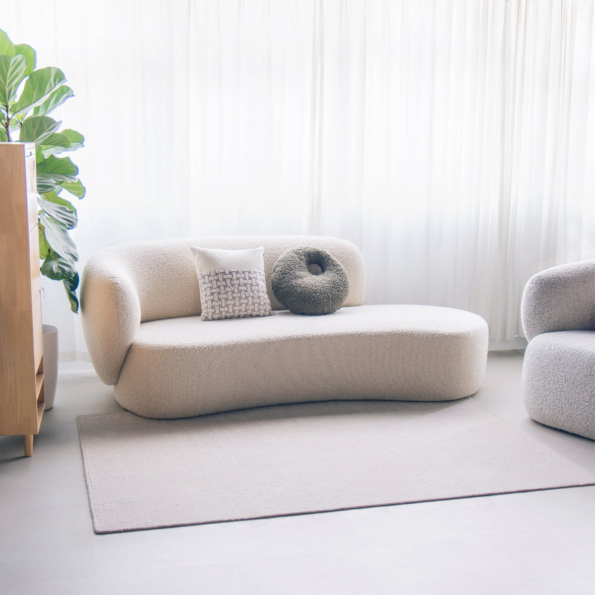 Modern living room with a beige sofa, decorative pillows, and a plant.