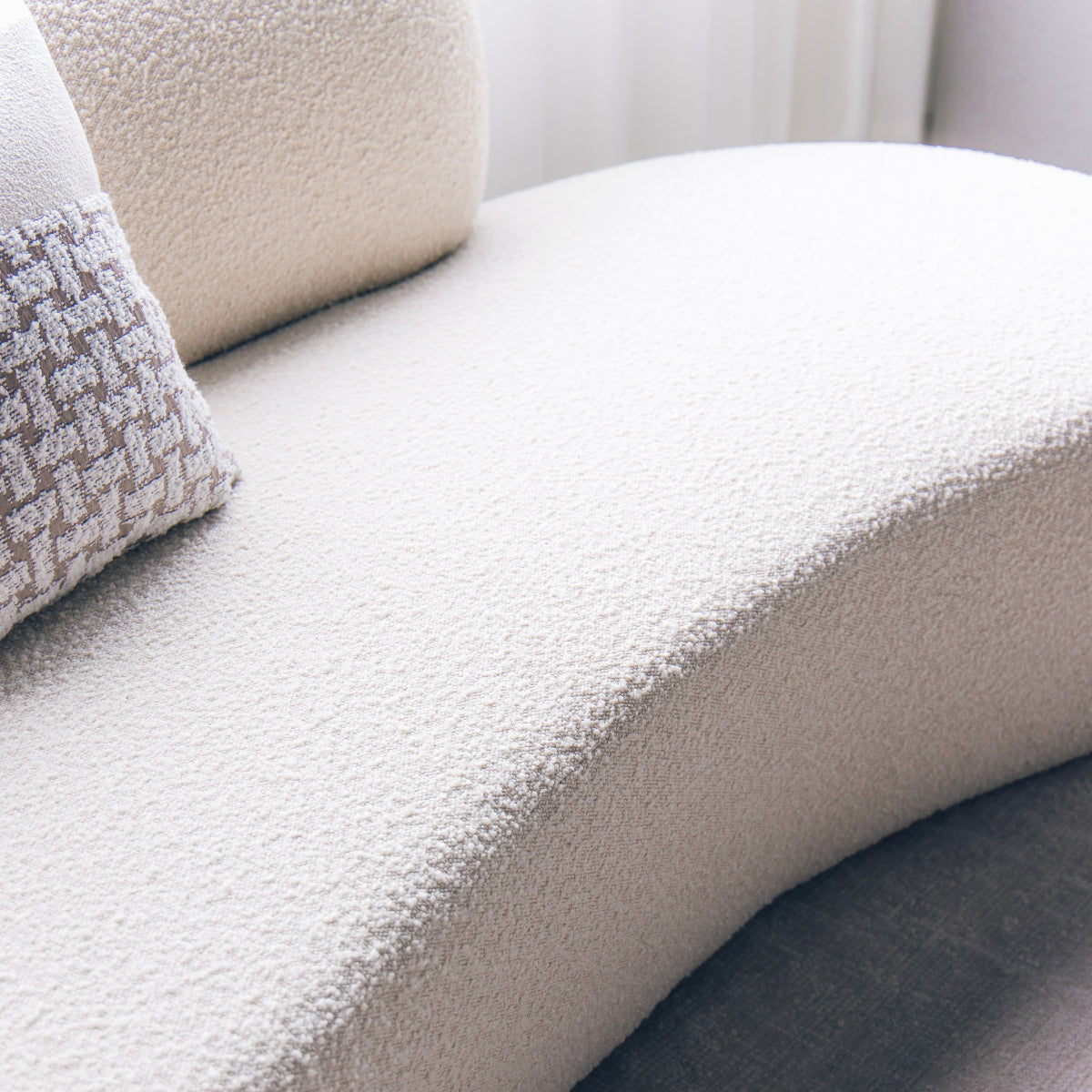 Close-up of a textured beige sofa with a pillow.