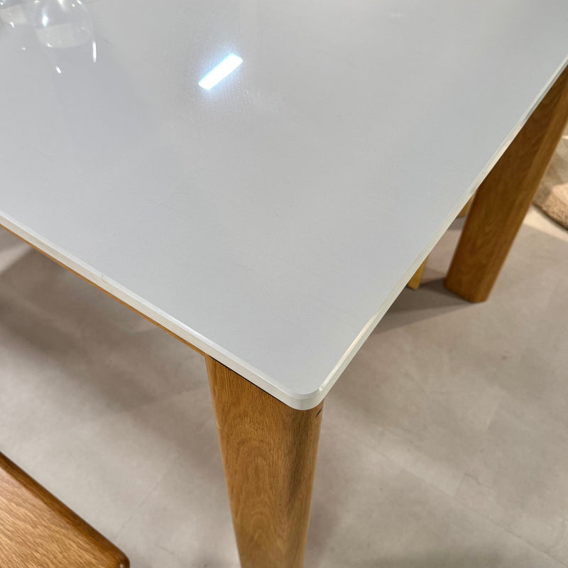 White dining table with wooden legs on a light-colored floor
