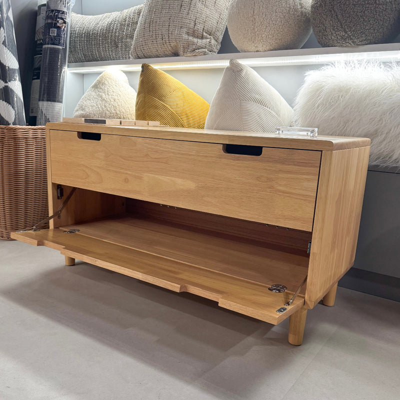 Wooden storage bench with open drawer in a room with pillows and a basket.
