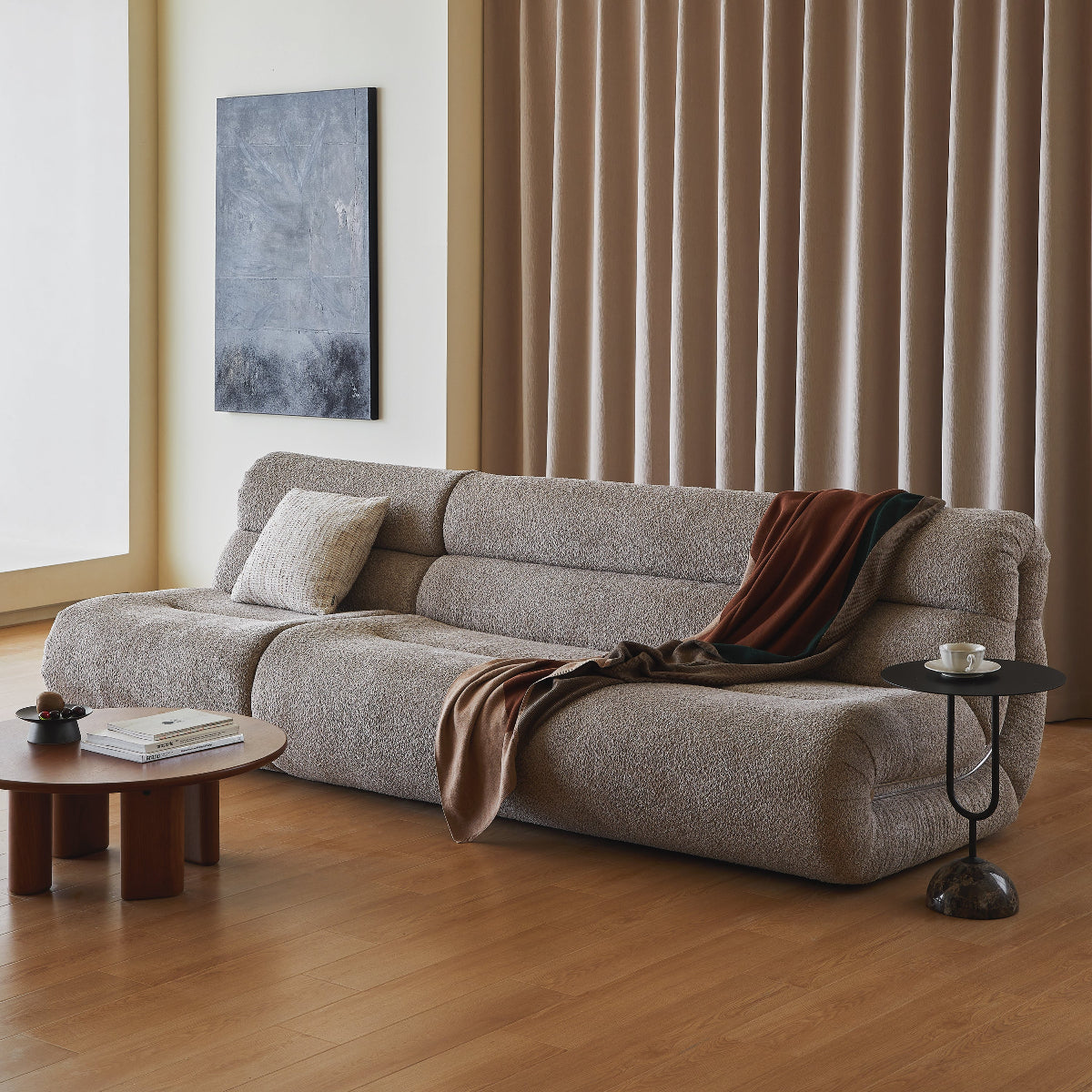 Modern living room with a gray sofa, wooden coffee table, and abstract painting.