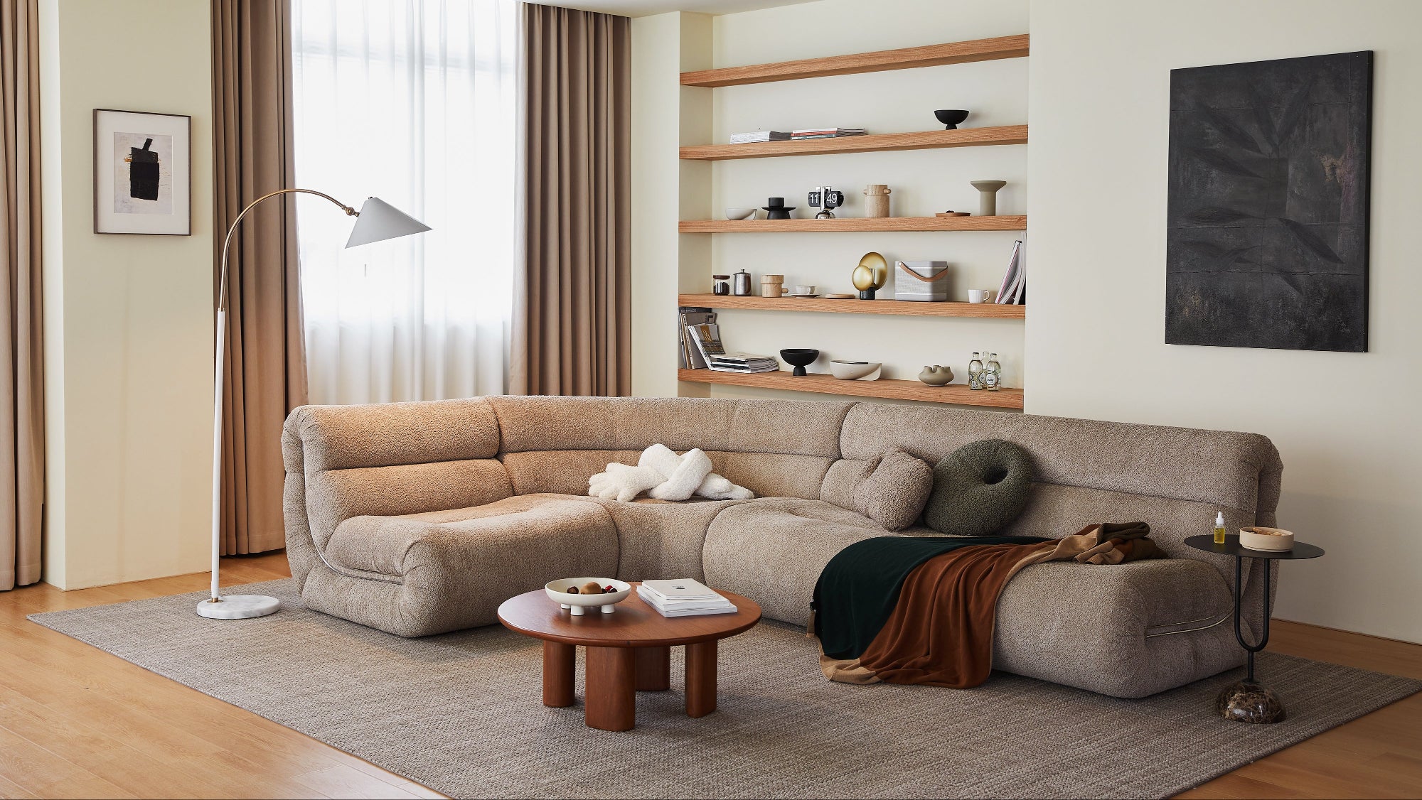 Modern living room with a beige sectional sofa, wooden coffee table, and shelves.
